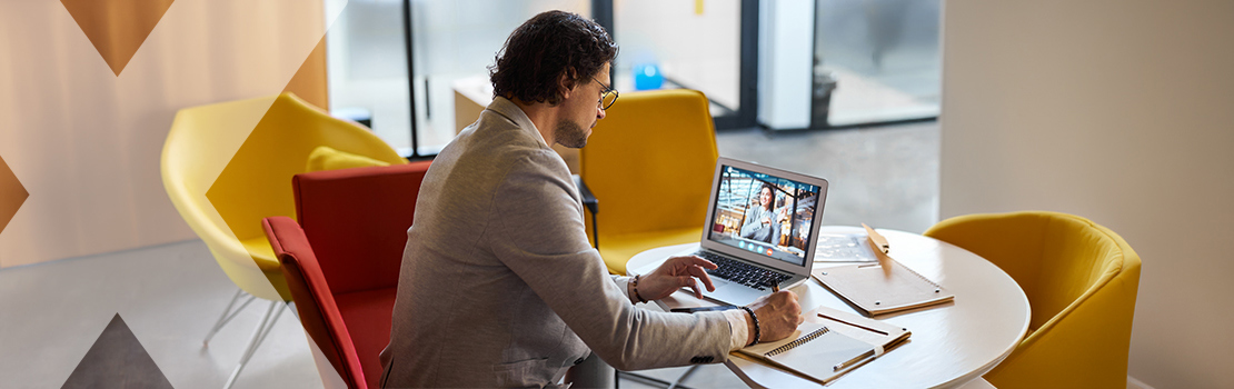 A person working in a remote work pod on a laptop video call with their manager, having a conversation about remote team building and team morale