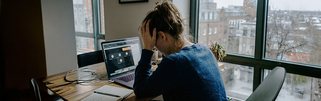 An stressed remote employee with their head in their hands, showing how excessive monitoring negatively impacts team morale