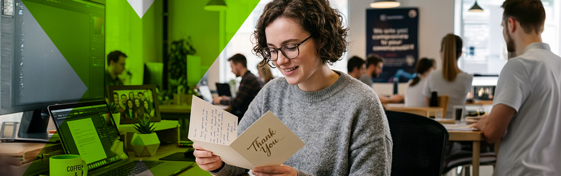 An employee reading a personalised "thank you" card at their desk, which is an example of a non-financial reward