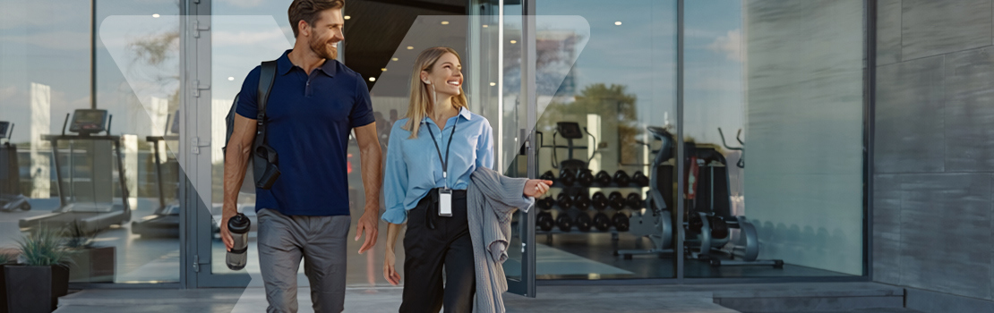 Two happy employees leaving a gym together, demonstrating the benefits of offering employee gym memberships