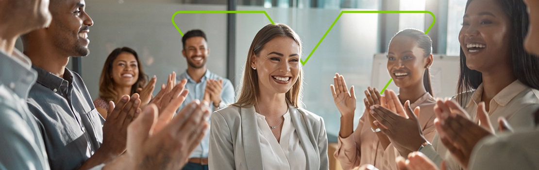 A smiling employee surrounded by clapping colleagues, showing how milestone celebrations are part of employee recognition and employee rewards