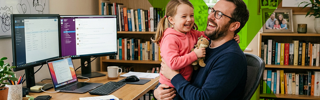 A father in their home office, laughing and playing with their child, showing how flexible working is a great way to show employee support for parents